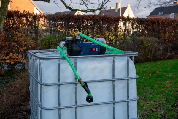 ibc-container-wit-met-pomp-accu-1000L-gereinigd-pallet-metaal-of-kunststof-linkerzijaanzicht-tuinomgeving-met-slang.webp