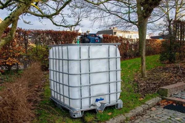 ibc-container-wit-met-pomp-accu-1000L-gereinigd-pallet-metaal-of-kunststof-linkerzijaanzicht-tuinomgeving-zonder-slang.webp